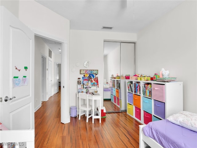 bedroom with a closet, visible vents, and wood finished floors