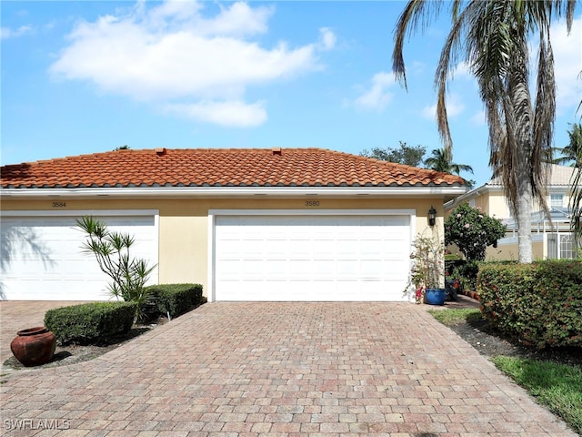 view of front facade featuring a garage, a tile roof, and stucco siding