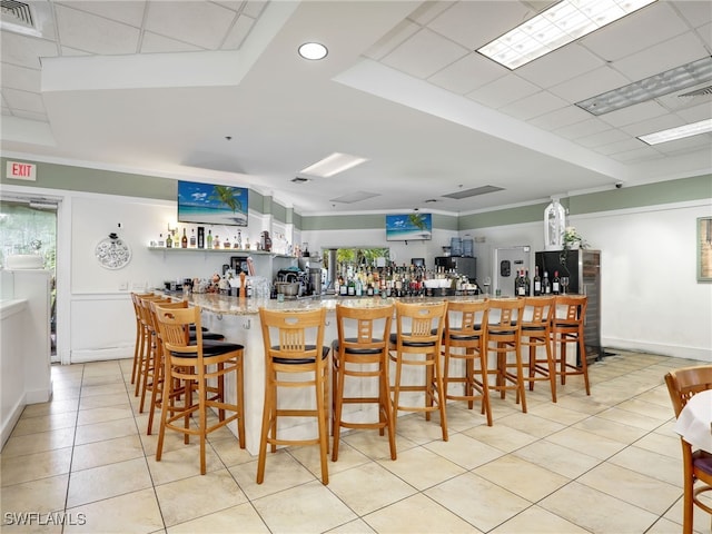 bar with a bar, light tile patterned floors, and visible vents