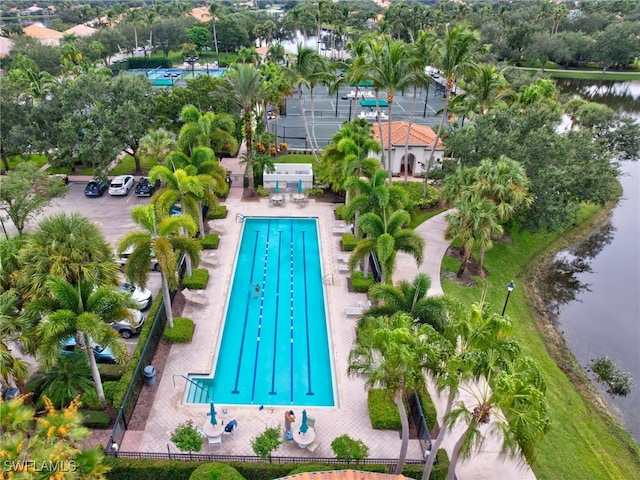 community pool with a water view, fence, and a patio