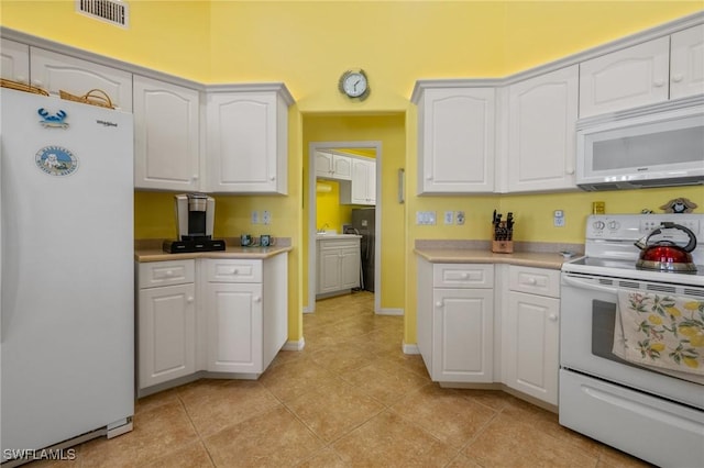 kitchen with light tile patterned floors, white appliances, and white cabinets