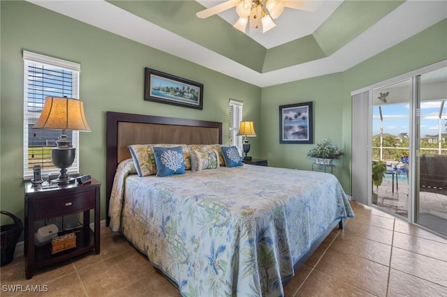 bedroom featuring a tray ceiling, access to exterior, tile patterned flooring, and multiple windows