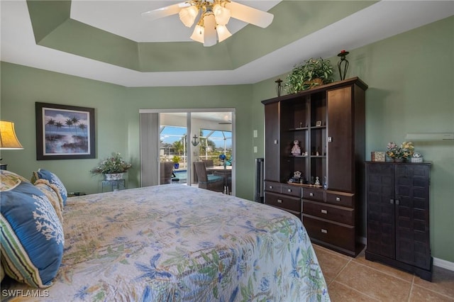 tiled bedroom featuring access to exterior, a raised ceiling, and ceiling fan