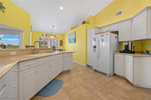 kitchen featuring vaulted ceiling, white refrigerator with ice dispenser, white cabinets, and decorative light fixtures