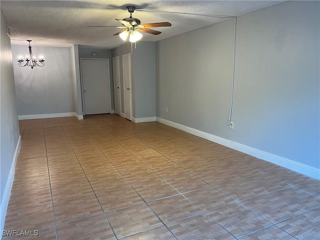 tiled empty room featuring ceiling fan with notable chandelier and a textured ceiling