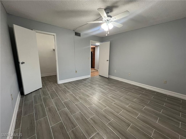 unfurnished bedroom with a textured ceiling, a walk in closet, and ceiling fan