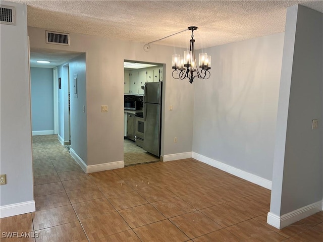 unfurnished dining area featuring light tile patterned floors, a textured ceiling, and an inviting chandelier