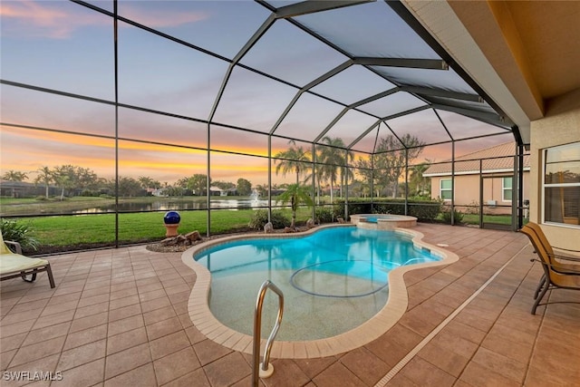 pool at dusk with glass enclosure, a pool with connected hot tub, a lawn, and a patio