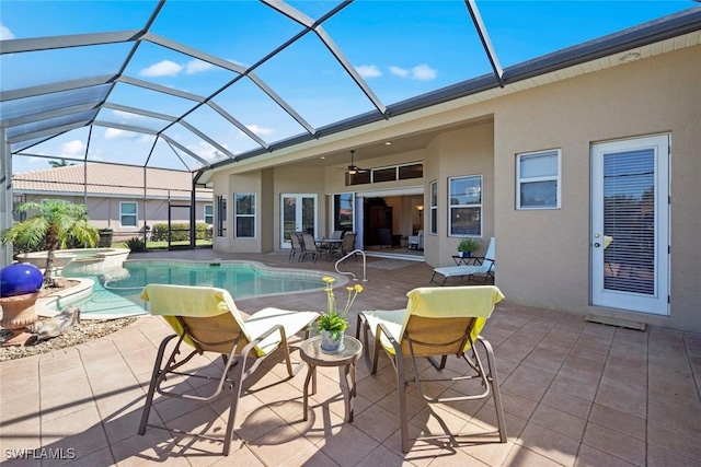 view of pool with glass enclosure, a pool with connected hot tub, a ceiling fan, and a patio