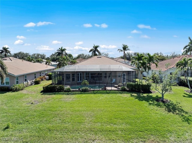 rear view of house with glass enclosure, a lawn, and a fenced in pool