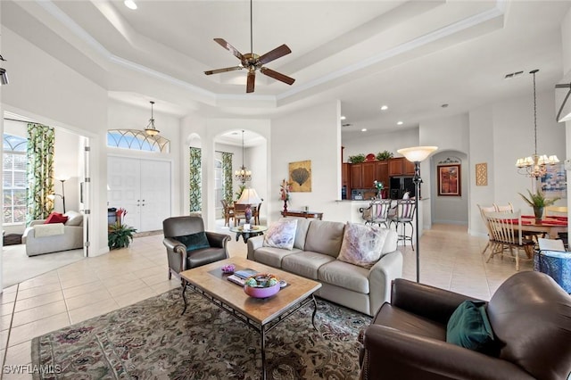 living area featuring arched walkways, light tile patterned flooring, a raised ceiling, and a towering ceiling