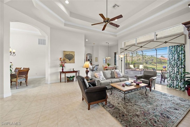 living room featuring visible vents, arched walkways, a tray ceiling, and light tile patterned flooring