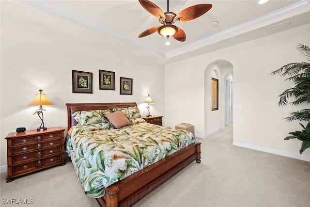 bedroom with arched walkways, light carpet, baseboards, ornamental molding, and a tray ceiling