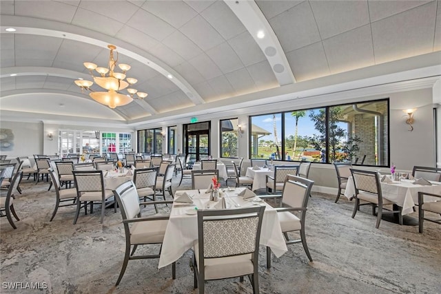 dining space featuring a chandelier, vaulted ceiling, plenty of natural light, and baseboards