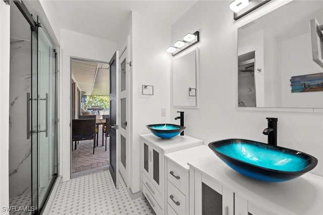 bathroom featuring two vanities, a sink, and a marble finish shower