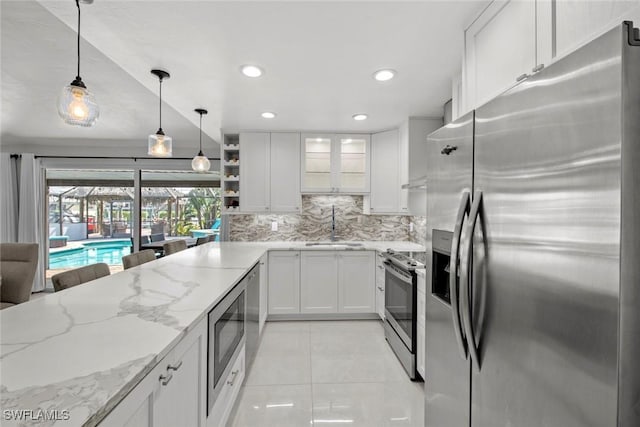 kitchen with glass insert cabinets, white cabinetry, appliances with stainless steel finishes, and hanging light fixtures