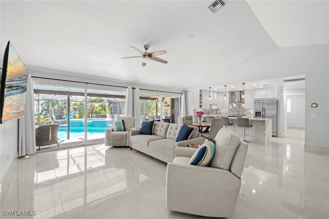 living area featuring lofted ceiling, ceiling fan, and visible vents