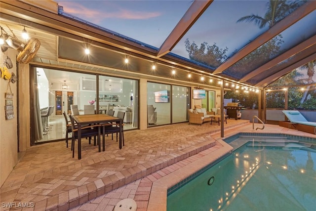 pool at dusk with glass enclosure, an outdoor pool, and a patio