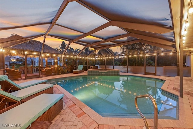 view of swimming pool featuring a lanai, a pool with connected hot tub, and a patio