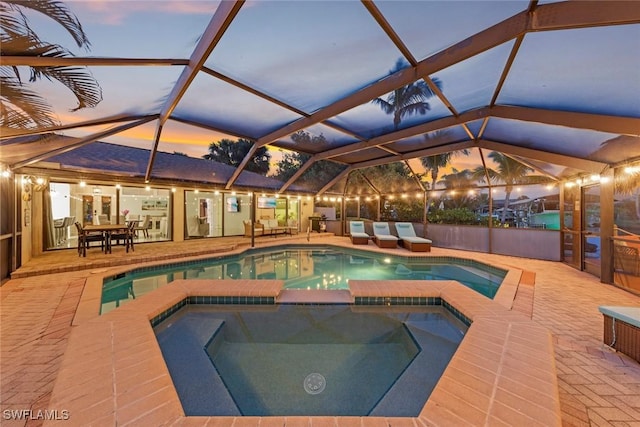 view of swimming pool with glass enclosure, a patio area, and a pool with connected hot tub