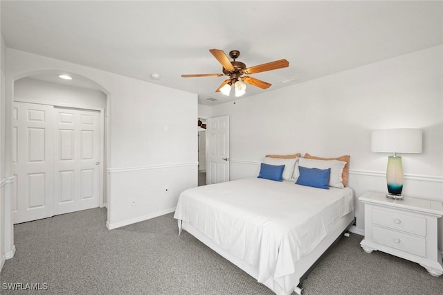 carpeted bedroom featuring arched walkways, a ceiling fan, and baseboards