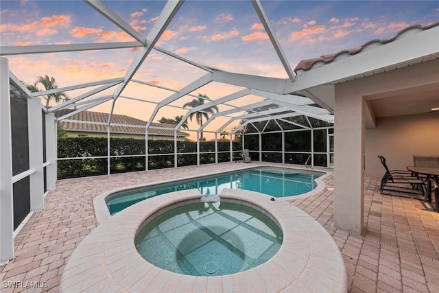 view of pool featuring a patio area, a pool with connected hot tub, and glass enclosure