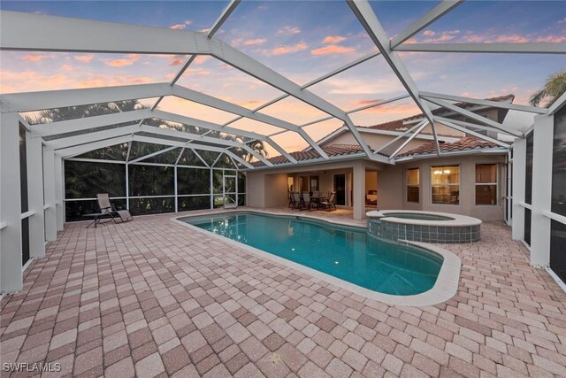 view of pool with a lanai, a pool with connected hot tub, and a patio