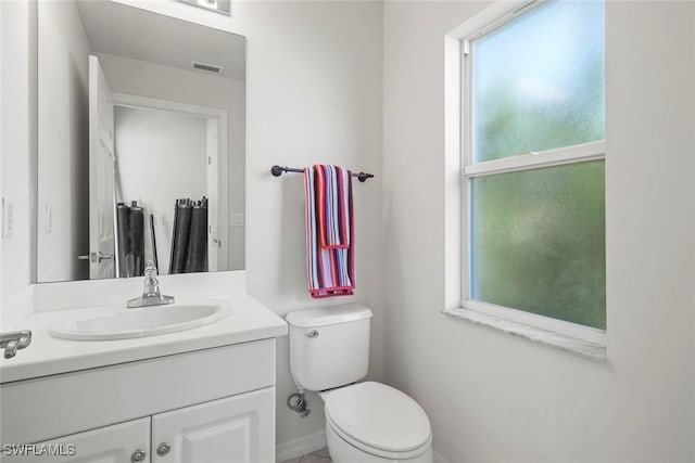 bathroom with a wealth of natural light, visible vents, vanity, and toilet