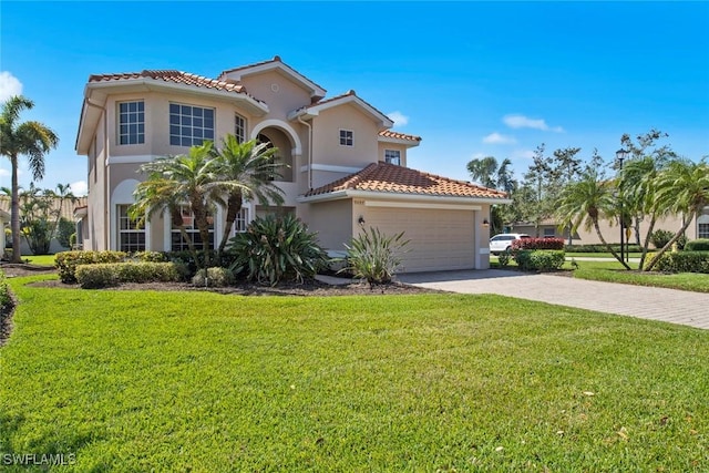 mediterranean / spanish-style home with a garage, a tile roof, driveway, stucco siding, and a front lawn