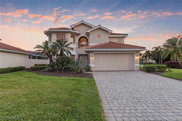 mediterranean / spanish home featuring a garage, a front lawn, decorative driveway, and stucco siding