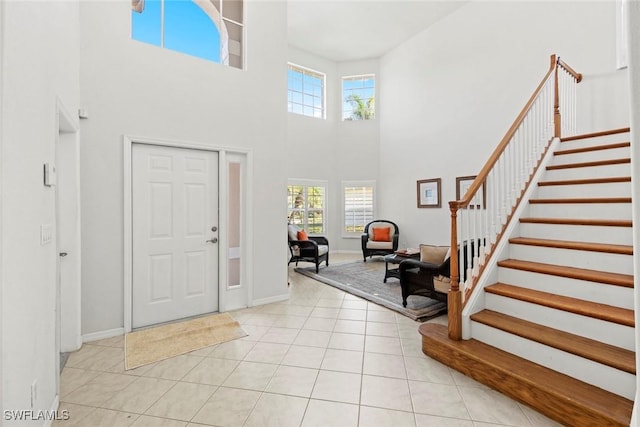 entryway with a high ceiling, light tile patterned flooring, stairway, and baseboards