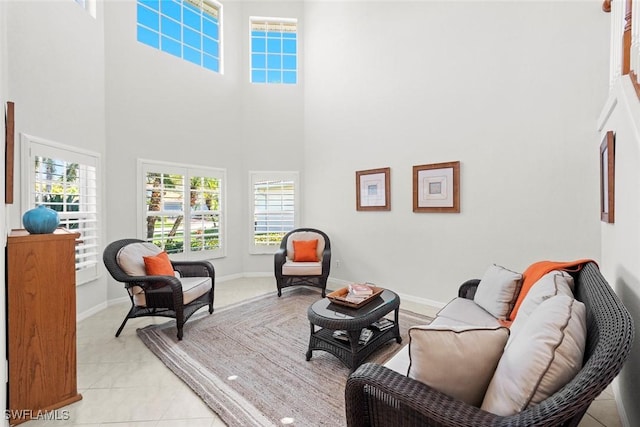 living area featuring a high ceiling, baseboards, and light tile patterned floors