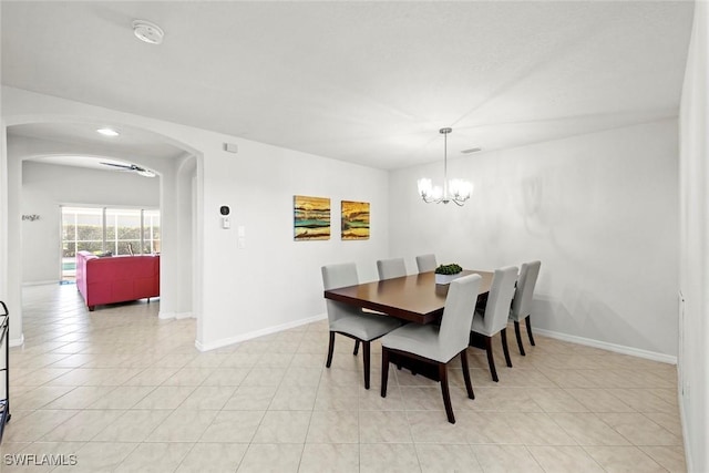 dining room featuring arched walkways, light tile patterned floors, a chandelier, and baseboards