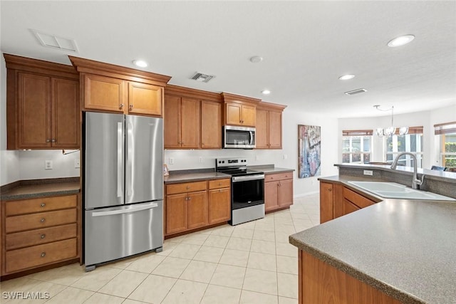 kitchen featuring visible vents, appliances with stainless steel finishes, brown cabinets, and a sink