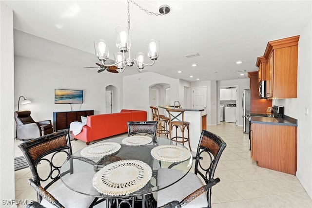 dining area featuring arched walkways, washing machine and clothes dryer, light tile patterned floors, recessed lighting, and an inviting chandelier