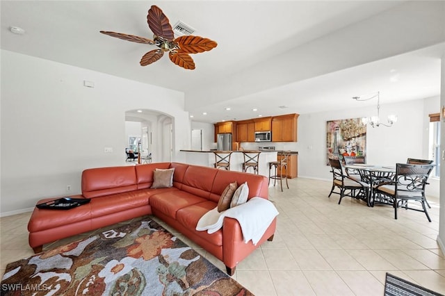 living area featuring arched walkways, light tile patterned floors, ceiling fan with notable chandelier, and visible vents