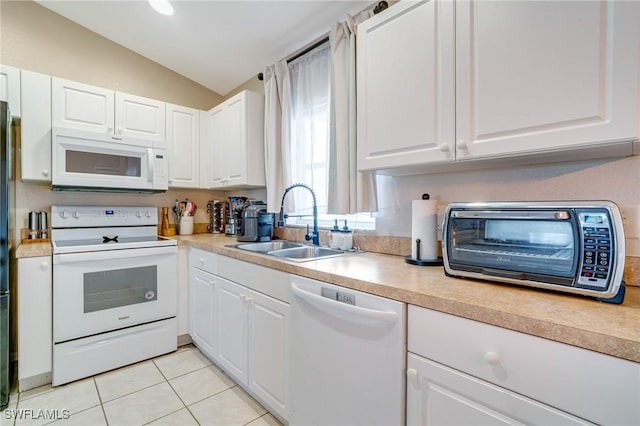 kitchen featuring light tile patterned floors, white appliances, a sink, and white cabinetry