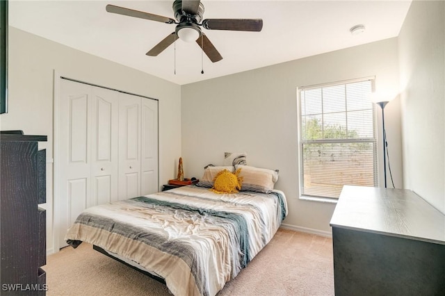 bedroom featuring ceiling fan, baseboards, a closet, and light colored carpet