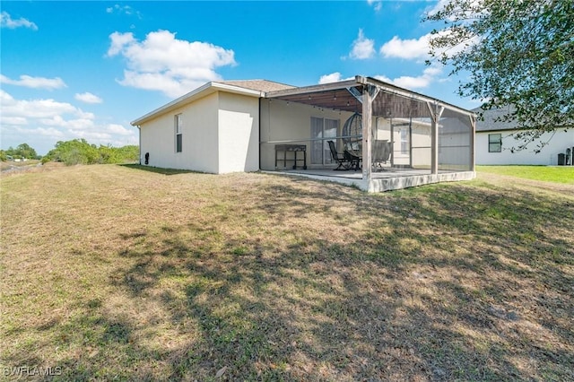 back of property featuring a lawn, a patio area, and stucco siding