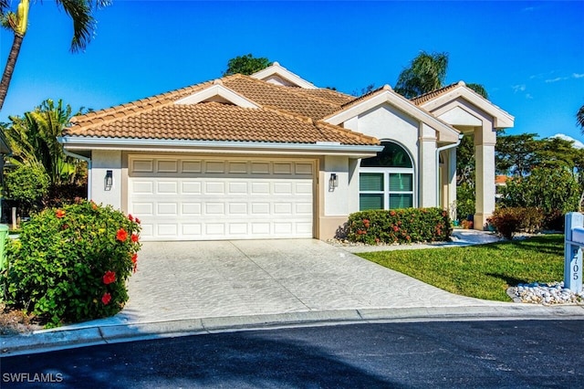 mediterranean / spanish-style house with driveway, a tiled roof, and stucco siding