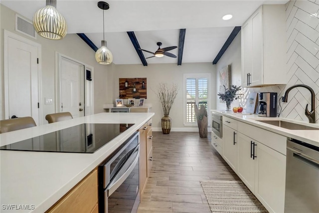 kitchen featuring pendant lighting, sink, appliances with stainless steel finishes, beam ceiling, and decorative backsplash