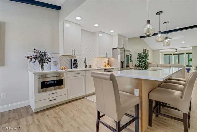 kitchen with white cabinetry, appliances with stainless steel finishes, decorative light fixtures, and a kitchen island