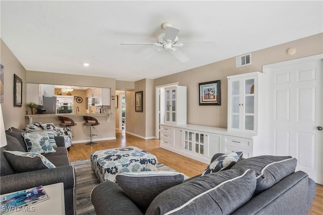 living room with visible vents, a ceiling fan, light wood-type flooring, and baseboards