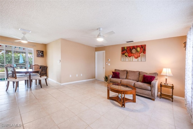 living area featuring baseboards, a textured ceiling, visible vents, and a ceiling fan