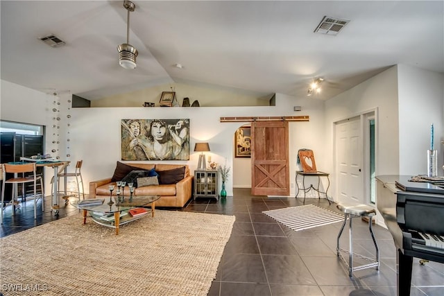 living room with dark tile patterned floors, a barn door, and lofted ceiling