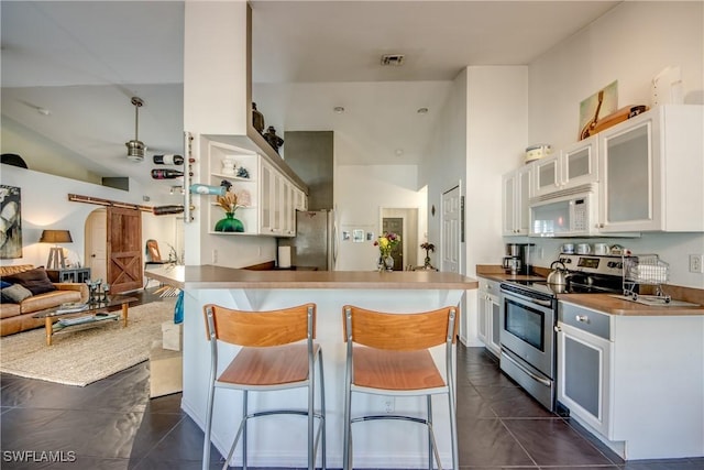 kitchen with a breakfast bar area, white cabinetry, appliances with stainless steel finishes, kitchen peninsula, and a barn door