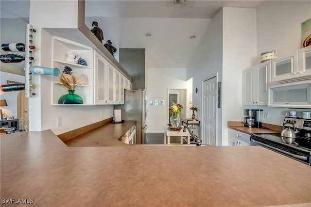 kitchen featuring a high ceiling, appliances with stainless steel finishes, sink, and white cabinets