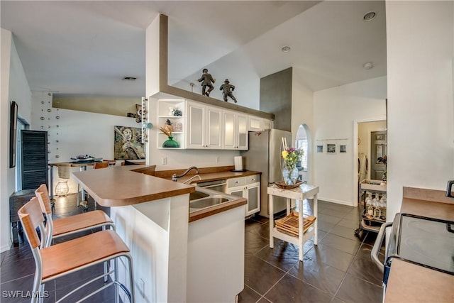 kitchen with electric stove, sink, stainless steel refrigerator, a breakfast bar, and kitchen peninsula