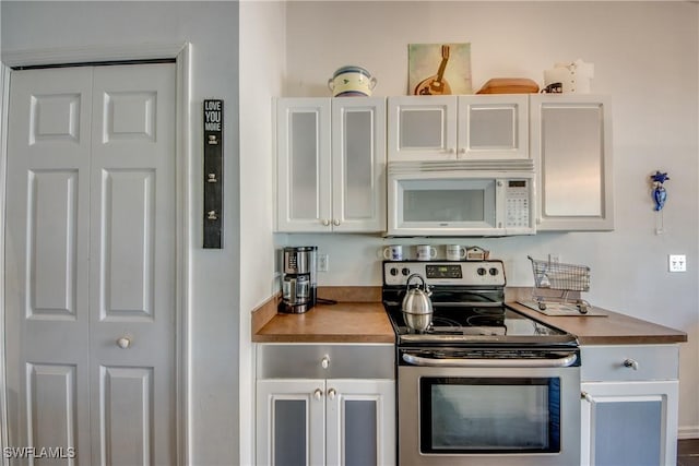 kitchen featuring electric range, wooden counters, and white cabinets