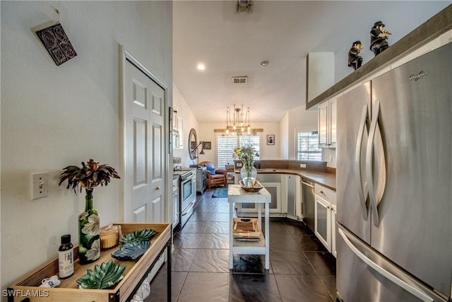 kitchen with stainless steel appliances, white cabinetry, a chandelier, and kitchen peninsula